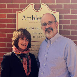 Pg 16 About Us-Our History-Maryellen and Bill in front of Plaque